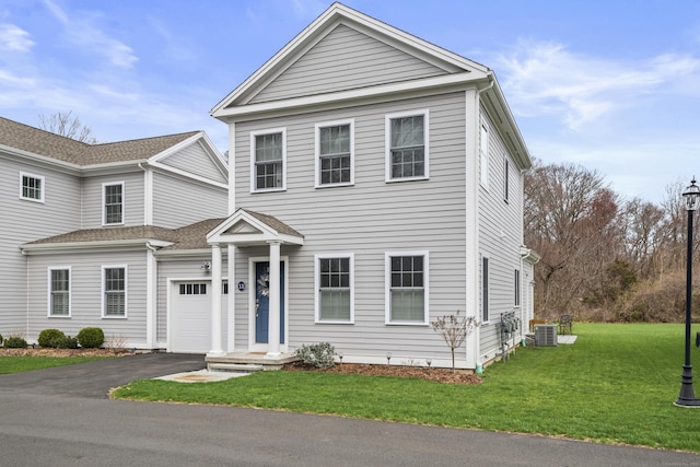 view of front facade featuring central air condition unit, an attached garage, a front yard, and aphalt driveway