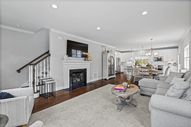 living room with crown molding, recessed lighting, an inviting chandelier, and dark wood-style floors