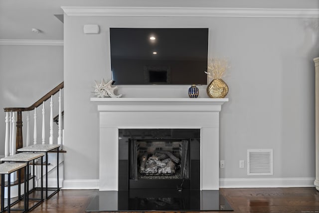 details with crown molding, a fireplace, baseboards, wood finished floors, and visible vents
