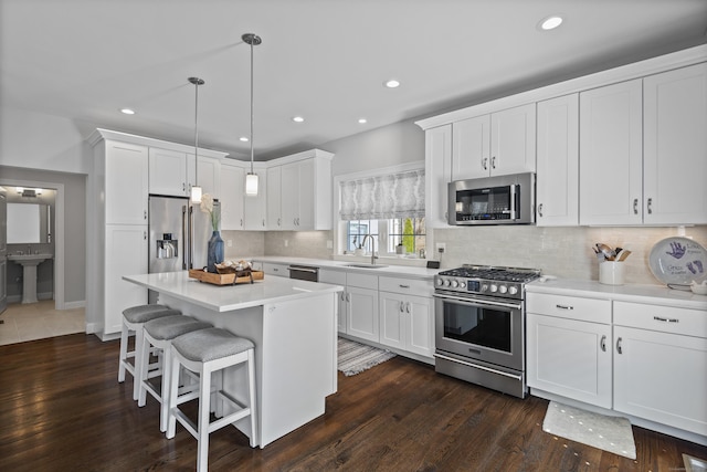 kitchen with white cabinetry, appliances with stainless steel finishes, a sink, and a kitchen bar
