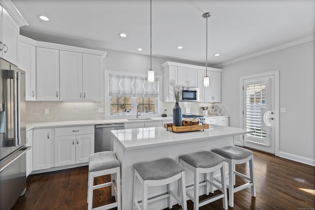 kitchen featuring backsplash, stainless steel appliances, white cabinetry, and a kitchen breakfast bar