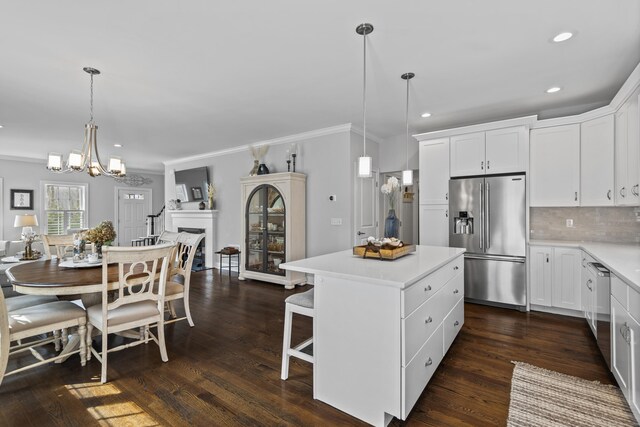 kitchen featuring appliances with stainless steel finishes, light countertops, a chandelier, a center island, and ornamental molding