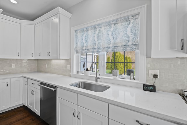 kitchen with white cabinets, decorative backsplash, a sink, and dishwasher