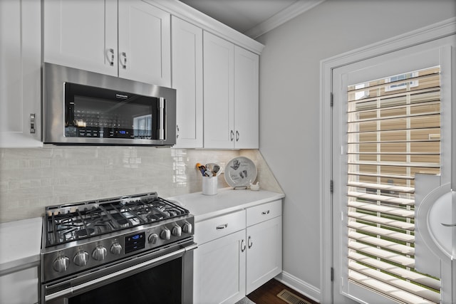 kitchen with crown molding, white cabinetry, appliances with stainless steel finishes, and a wealth of natural light