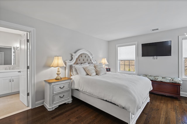bedroom with visible vents, baseboards, ensuite bathroom, and wood finished floors