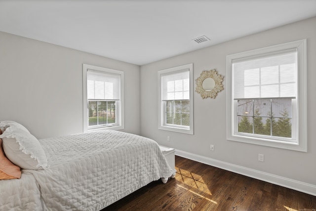 bedroom featuring baseboards, dark wood finished floors, and visible vents