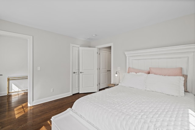 bedroom featuring dark wood-style flooring, baseboards, and a closet