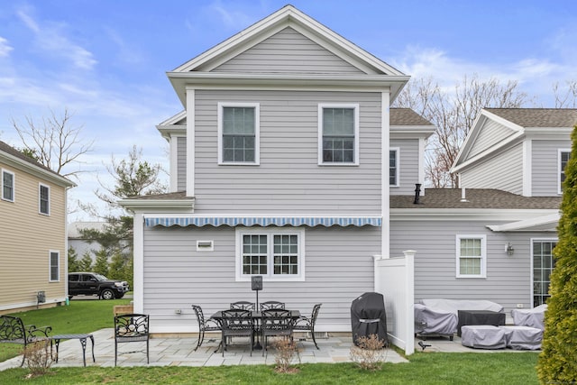 rear view of house with a patio, a shingled roof, and a yard