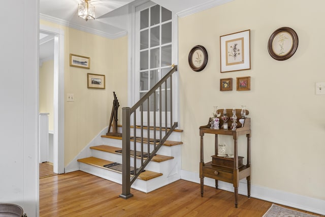 stairway featuring wood finished floors, crown molding, and baseboards