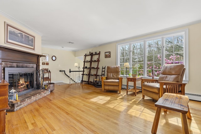 living area with a baseboard heating unit, wood finished floors, and crown molding