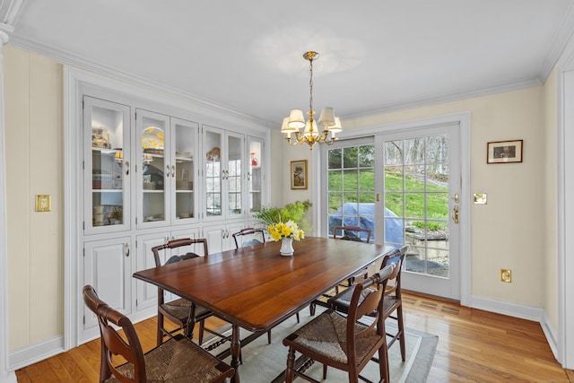 dining space featuring light wood finished floors, baseboards, a notable chandelier, and ornamental molding