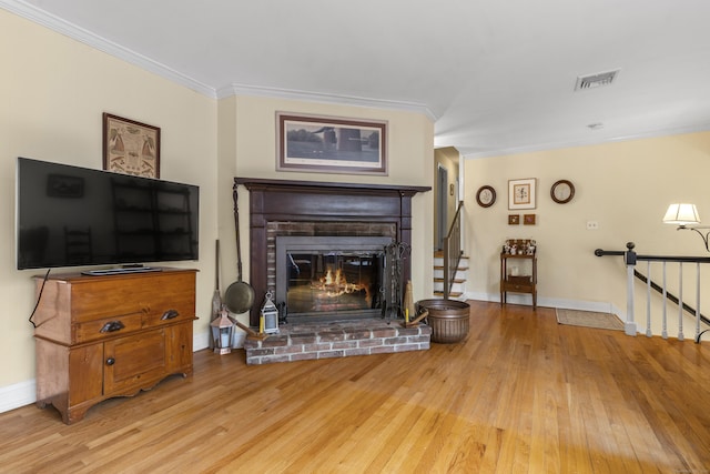 living room featuring ornamental molding, wood finished floors, visible vents, and a fireplace