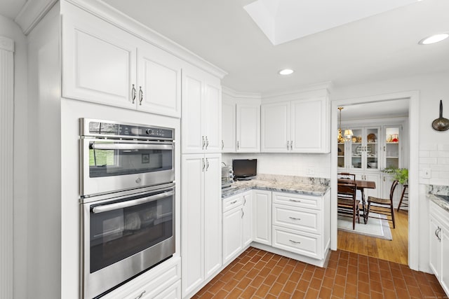kitchen with recessed lighting, white cabinetry, stainless steel double oven, and decorative backsplash