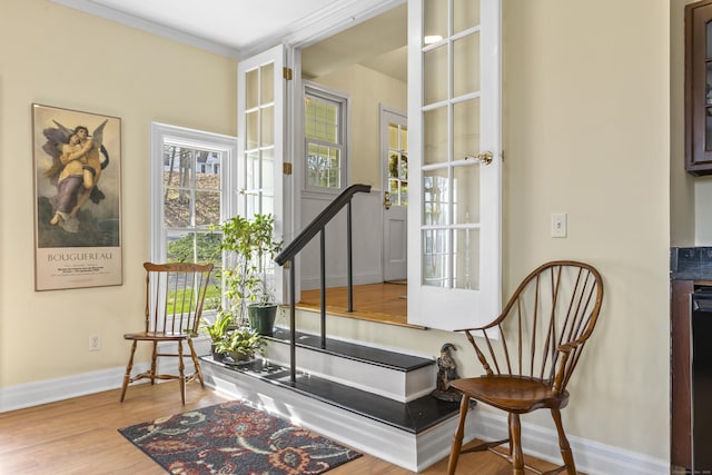 sitting room featuring baseboards, crown molding, and wood finished floors