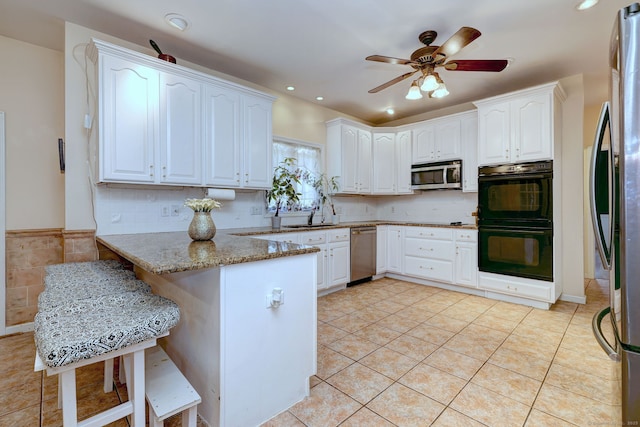 340 Webb Cir, Monroe, CT 06468 - kitchen featuring a peninsula, light tile patterned flooring, white cabinetry, light stone counters, and appliances with stainless steel finishes