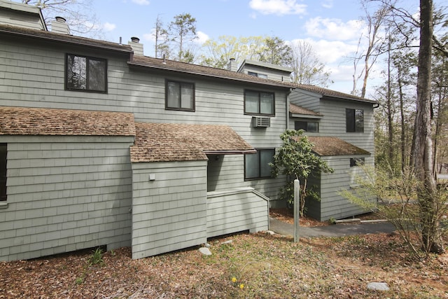 back of house featuring a chimney and an AC wall unit