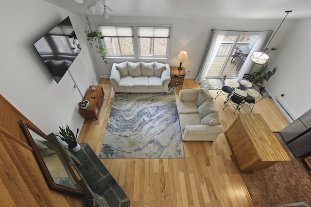 living room featuring wood finished floors, a baseboard heating unit, rail lighting, and plenty of natural light