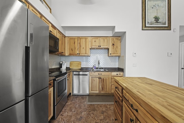 kitchen featuring wood counters, stainless steel appliances, stone finish flooring, backsplash, and a sink