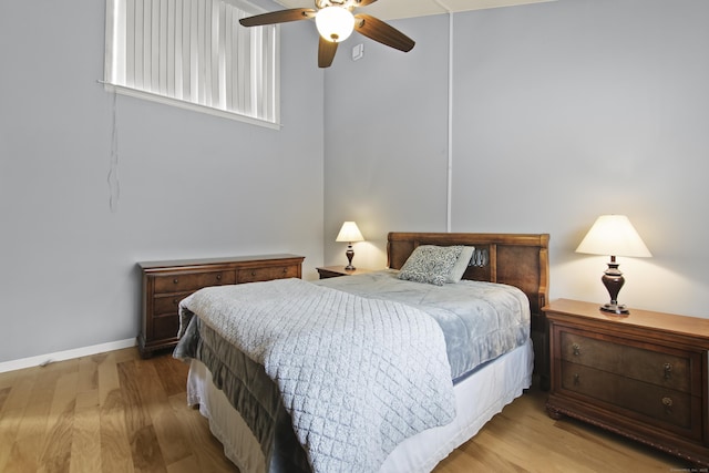bedroom with a ceiling fan, wood finished floors, and baseboards