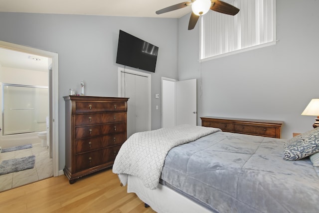 bedroom featuring ensuite bath, a closet, wood finished floors, a ceiling fan, and high vaulted ceiling