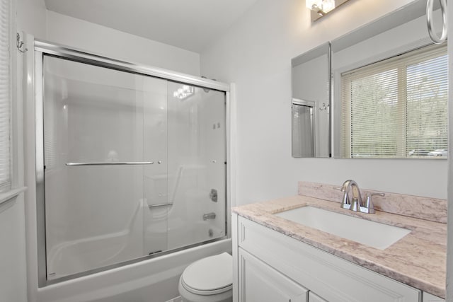 bathroom with toilet, combined bath / shower with glass door, and vanity