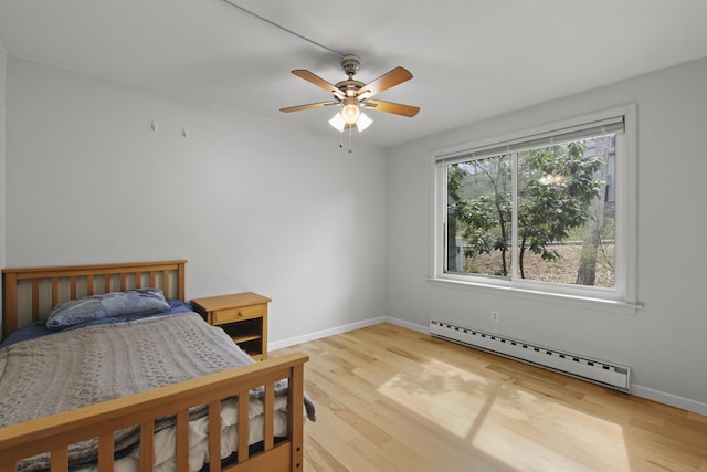 bedroom featuring baseboards, wood finished floors, a ceiling fan, and a baseboard radiator