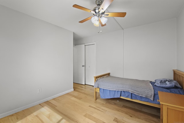 bedroom with baseboards, light wood-type flooring, ceiling fan, and a closet