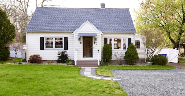cape cod home with fence, roof with shingles, a chimney, and a front lawn