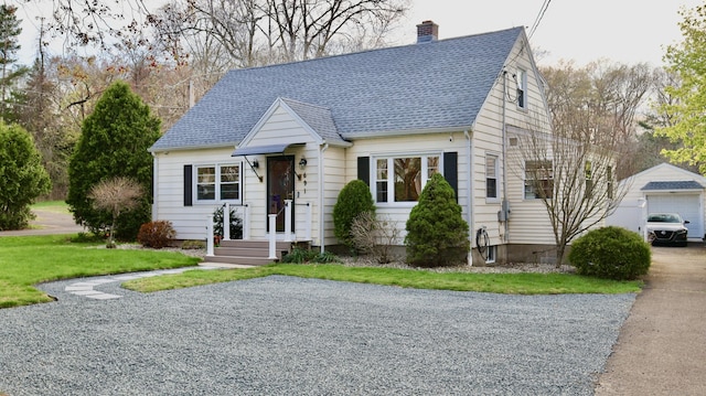 view of front of property with an outbuilding, a front yard, roof with shingles, and a chimney