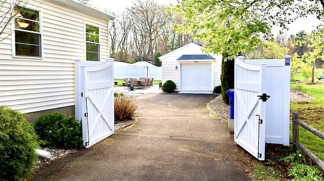 exterior space with fence, a gate, and aphalt driveway
