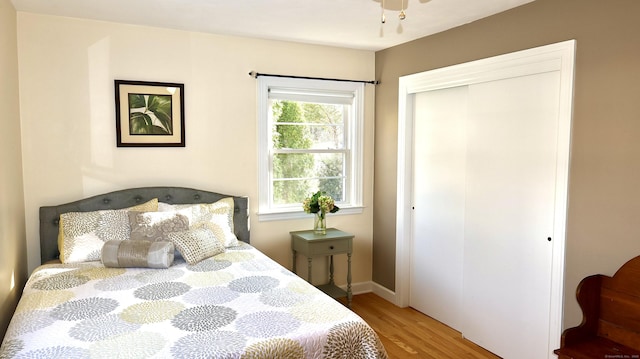 bedroom with baseboards, light wood-type flooring, and a closet