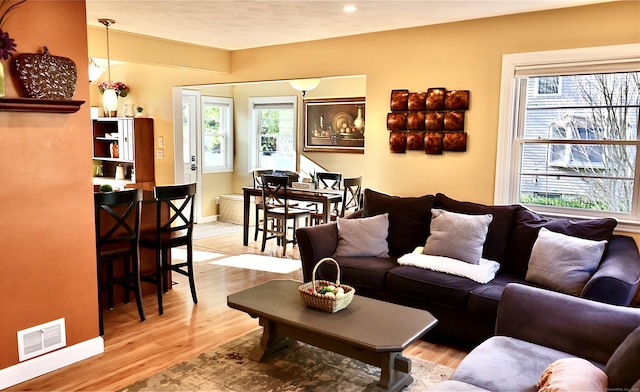 living area featuring visible vents, baseboards, recessed lighting, and light wood-style floors