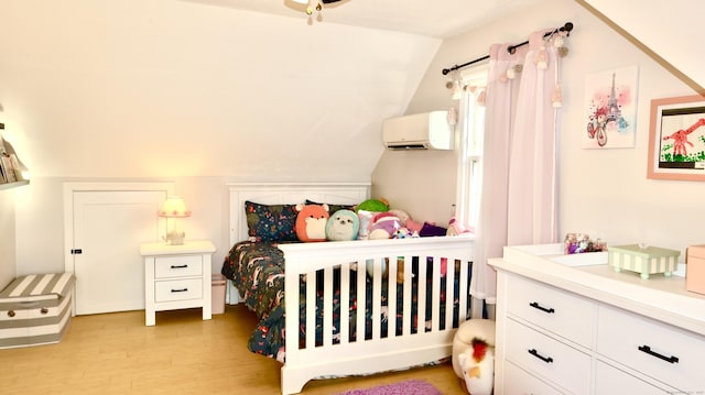 bedroom featuring a wall mounted air conditioner, light wood-style floors, and vaulted ceiling