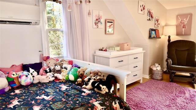 bedroom with wood finished floors and a wall mounted AC