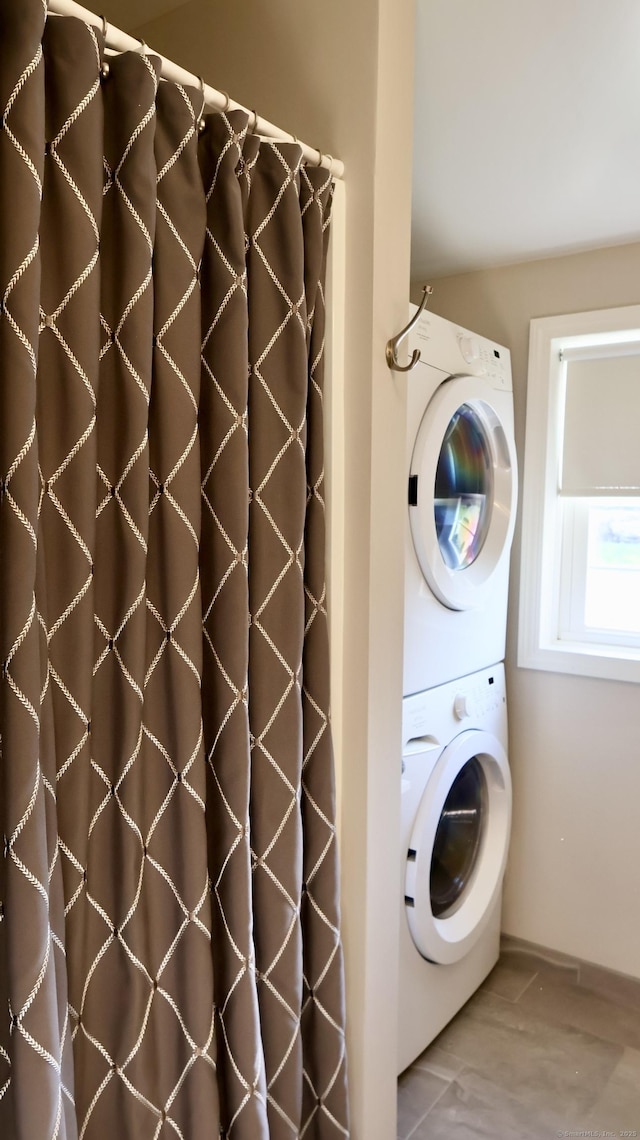 laundry room with baseboards, stacked washer and dryer, and laundry area