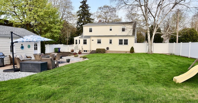 back of house featuring a chimney, a patio area, outdoor lounge area, a lawn, and a fenced backyard