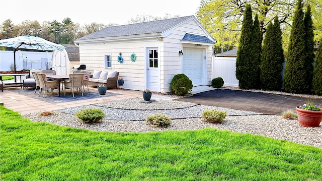 exterior space featuring fence, an outdoor structure, and driveway