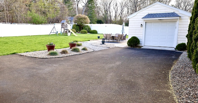 detached garage featuring fence and driveway