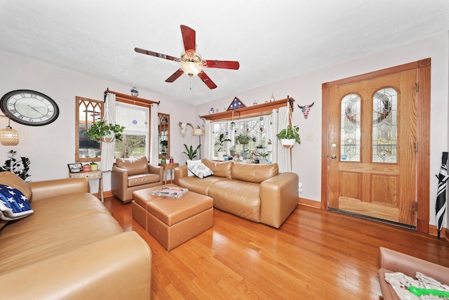 living area featuring light wood-type flooring, a healthy amount of sunlight, baseboards, and ceiling fan