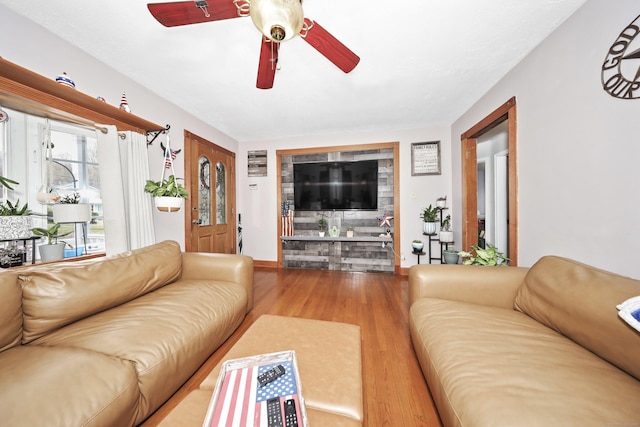 living room featuring baseboards, a ceiling fan, and wood finished floors