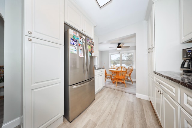 kitchen with light wood finished floors, baseboards, freestanding refrigerator, and white cabinetry