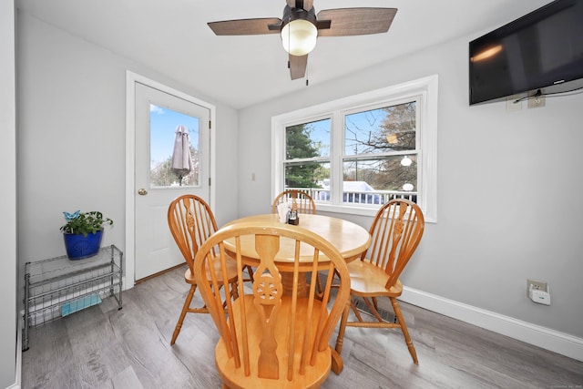 dining space with baseboards, a ceiling fan, and wood finished floors