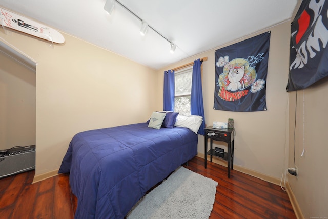 bedroom featuring wood finished floors, rail lighting, and baseboards