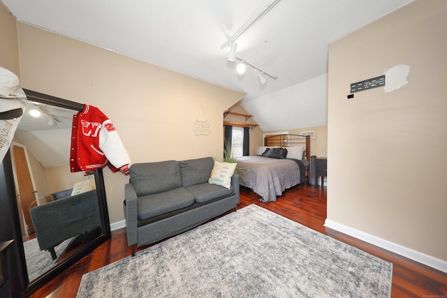 bedroom with track lighting, wood finished floors, lofted ceiling, and baseboards