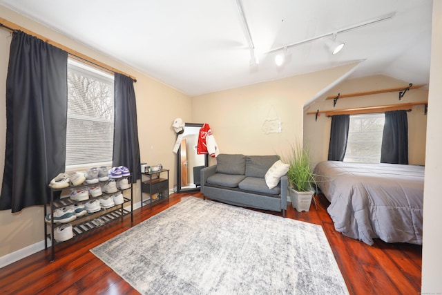 bedroom with lofted ceiling, baseboards, track lighting, and wood finished floors