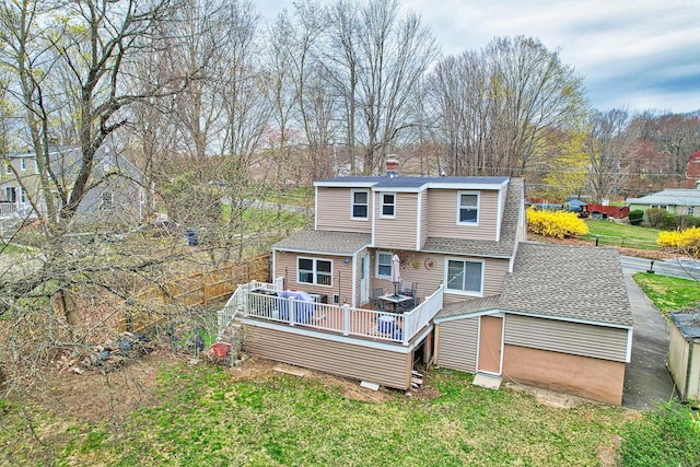 rear view of property with a chimney, a yard, a shed, roof with shingles, and a deck