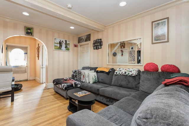 living room featuring arched walkways, crown molding, wood finished floors, and wallpapered walls