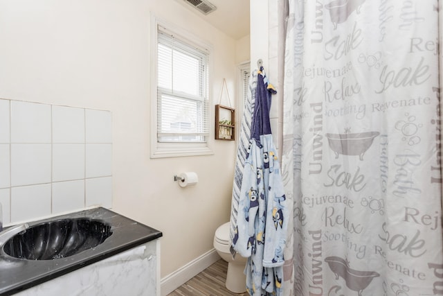 full bathroom with wood finished floors, curtained shower, baseboards, toilet, and visible vents