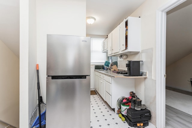 kitchen with white cabinets, freestanding refrigerator, light countertops, and light floors