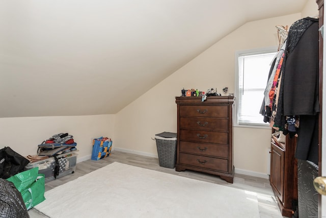 interior space featuring light wood finished floors, vaulted ceiling, and baseboards